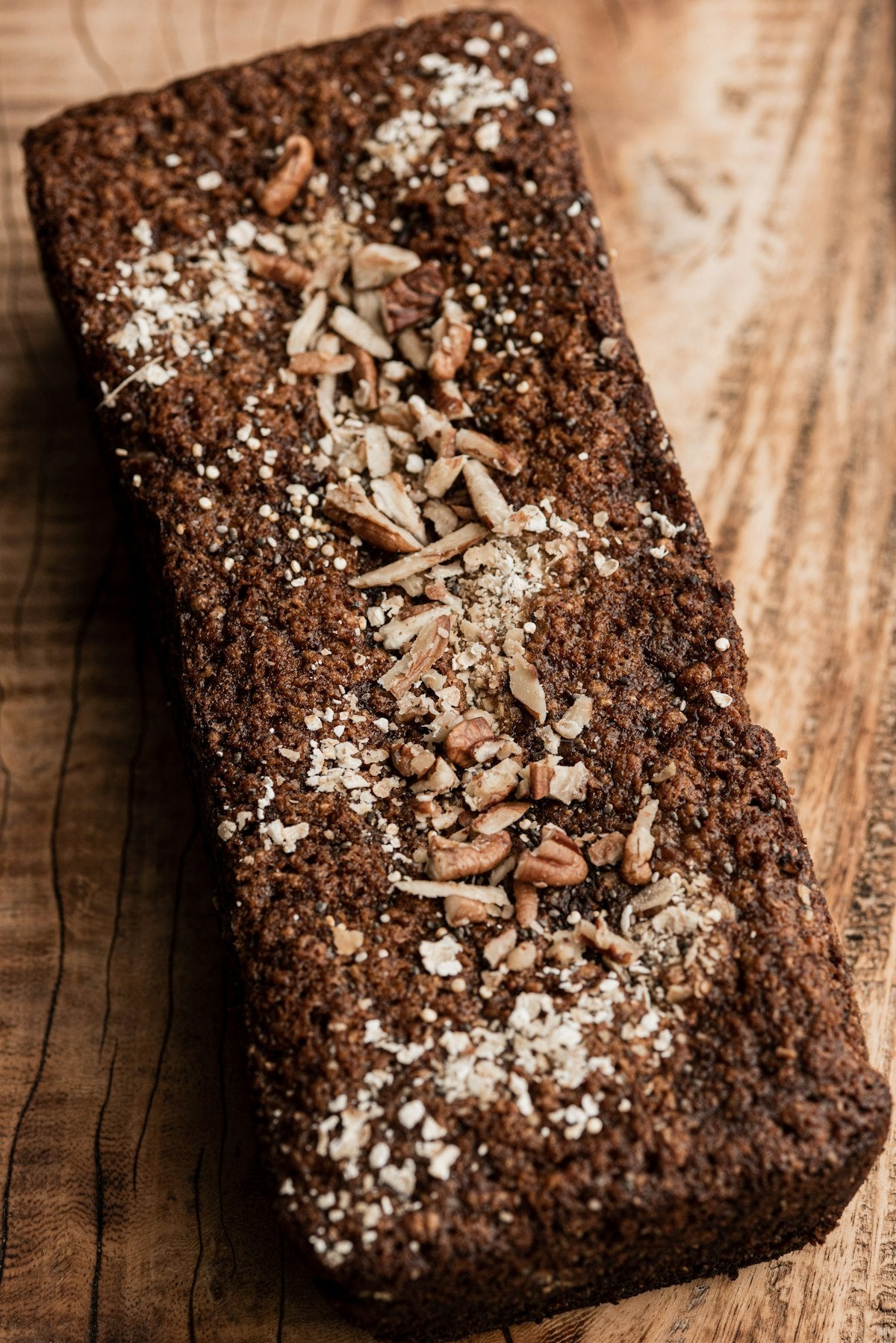 dunkles vollkornbrot mit pekannuessen und haferflocken auf warmem holz, alphavital