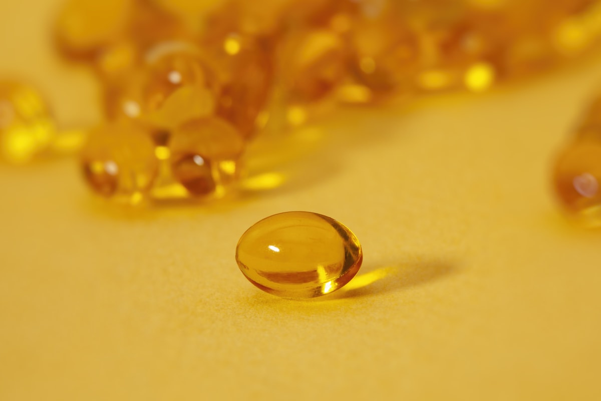 Goldene Öl-Softgel-Kapsel im warmen Licht, Symbol für alphavital Co Enzym Q10 Zellenergie