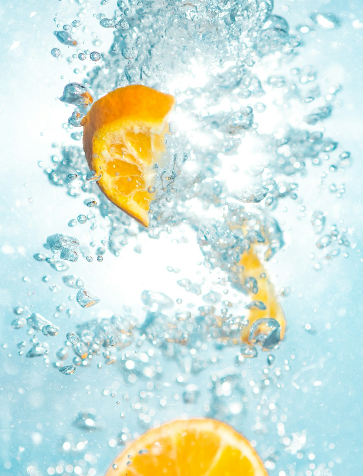 orangenstücke spritzen ins helle wasser, frische vitamin-c-assoziation für alphavital